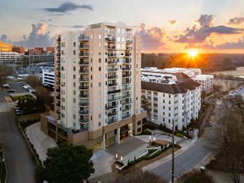 A tall apartment building with a sunset in the background.